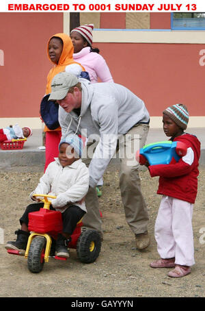 Prinz Harry schiebt die vierjährige Mojabeng auf ihren Traktor während eines Besuchs in der Lesotho Kinderberatung in Maseru, Lesotho, Afrika. Stockfoto