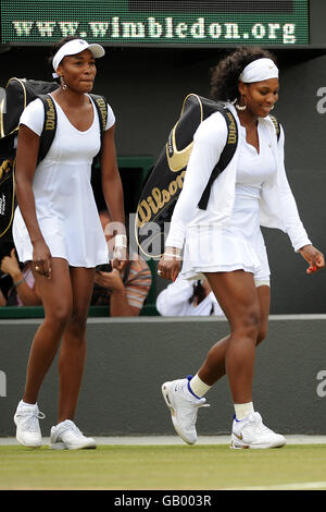 Die USA Serena (rechts) und Venus Williams betreten den Platz vor ihrem Doppelspiel bei den Wimbledon Championships 2008 im All England Tennis Club in Wimbledon. Stockfoto