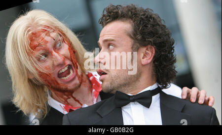 Der Schauspieler Alan M Crawford wird bei der Premiere von Nordirlands erstem Zombie-Horrorfilm „The Battle of the Bone“ in der Odyssey Arena, Belfast, von Zombie Johnny Burmside angegriffen. Stockfoto