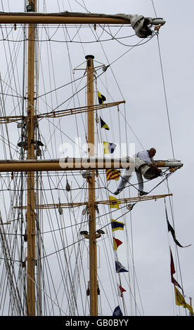 Segler packen die Segel auf einem im Albert Dock verankerten Schiff, das sich auf das Tall Ships Race Festival in Liverpool vorbereitet. Stockfoto