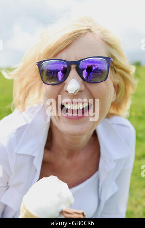 Schöne Frau genießen ein Eis Kornett mit Klecks am Ende der Nase lachen Stockfoto