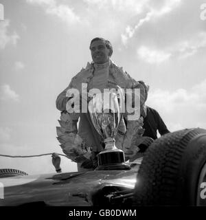 Der britische Jim Clark trägt die Girlande der Ehre und hält Seine Trophäe nach seinem Triumph im britischen Grand Prix In Silverstone in seinem Lotus Stockfoto