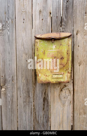 Alte grüne rostenden Metall Briefkasten auf ein Alter verblasst nach Hause Holzzaun. Vertikale Zusammensetzung mit niemand und Space-Bereich zu kopieren. Stockfoto