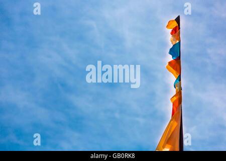 Ein Fahnenmast mit Fahnen und Wimpeln, die sich in einem blauen Himmel Stockfoto