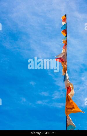 Ein Fahnenmast mit Fahnen und Wimpeln, die sich in einem blauen Himmel Stockfoto