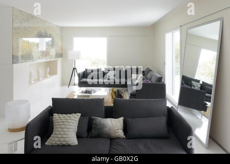 Modernes Wohnzimmer mit großen Sofas und hellen großen Fenstern Stockfoto