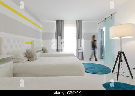 Bewegungsunscharfe Frau, die im Hotelzimmer mit zwei Betten spazieren geht Stockfoto