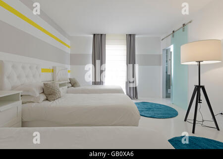 Drei Betten in einem sonnenbeleuchteten Hotelzimmer Stockfoto