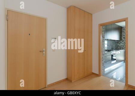 Eingangstür, schrank und offene Tür zur Küche einer Wohnung Stockfoto