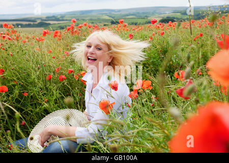 Schöne Frau unter Mohnfelder in der Nähe von Ditchling Beacon Sussex South Downs Way UK Stockfoto