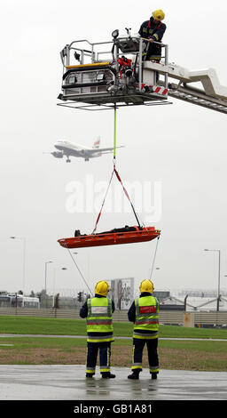 Feuerwehrleute nehmen an einer Übung in der neuen Feuerwache am Flughafen Heathrow, London, Teil, während ein Passagierflugzeug auf dem Hintergrund landet. Stockfoto