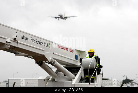 Ein Feuerwehrmann nimmt an einer Übung in der neuen Feuerwache am Londoner Flughafen Heathrow Teil, während ein Passagierflugzeug auf dem Hintergrund landet. Stockfoto