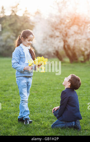 Junge das Mädchen Blumen gegeben und stand vor ihr auf seine Knie Stockfoto