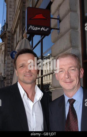 Alasdair Murdoch, Chief Executive von Pizza Hut bei Pat McFadden, Minister für Arbeitsbeziehungen (rechts) vor Pizza Hut in der Regent Street, London. Kundentipps in Bars und Restaurants werden nicht mehr auf die Bezahlung der Mitarbeiter angerechnet, um sie auf den Mindestlohn zu bringen, teilte die Regierung heute mit. Stockfoto