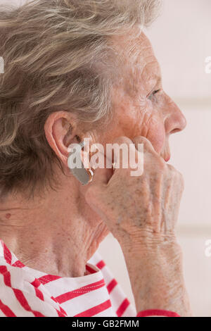 ältere Frau einfügen Hörgerät in ihr hören. Stockfoto