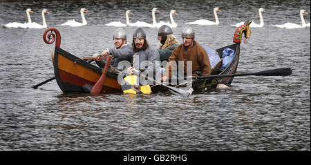 Enthusiasten des National Living History Festival am Lanark Loch in Schottland erleben eine Szene aus der Geschichte, als Wikingerraider in einem Langschiff an den Küsten Schottlands ankommen. Stockfoto