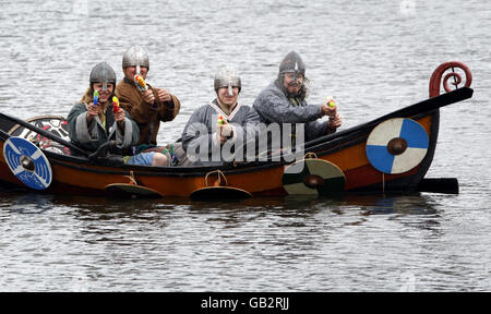 Enthusiasten des National Living History Festival am Lanark Loch in Schottland stellen eine Szene aus der Geschichte wieder auf, als Wikingerstreicher in einem Langschiff an den Küsten Schottlands ankommen - für eine freche Wendung sind die Wikinger mit Wasserpistolen statt Äxten und Schwertern bewaffnet. Stockfoto