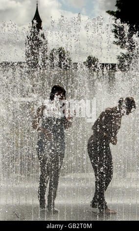 Mädchen spielen in den Springbrunnen vor der Hayward Gallery am Londoner Südufer, während die Londoner das sonnige Wetter genießen. Stockfoto