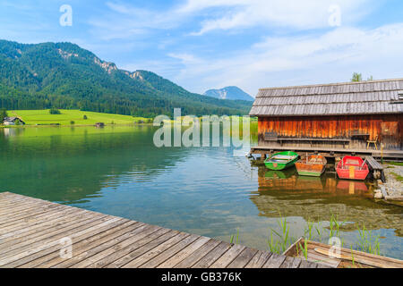 Holzsteg und Angelboote/Fischerboote mit Holzhäuser am Ufer des Weißensee in Sommerlandschaft Carinthia Land, Österreich Stockfoto