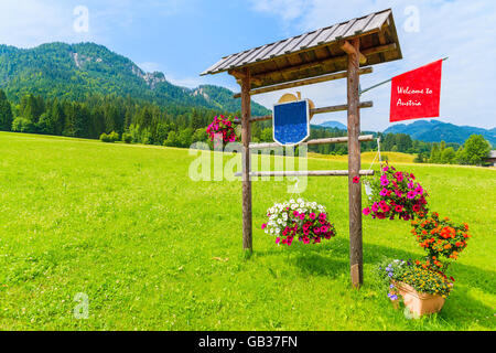 Holzschild "Willkommen Österreich" auf der grünen Wiese im Alpen Berge, Weißensee, Österreich Stockfoto