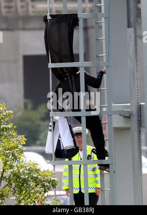 Ein Wahlkämpfer, der vermutlich mit Fathers 4 Justice verbunden ist, bekleidet, als Batman von einer Gantry über die M25 in der Nähe des Flughafens Heathrow, London, hinabklettert. Stockfoto