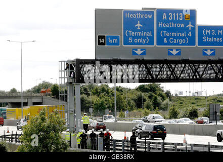 Ein Wahlkämpfer, der vermutlich mit Fathers 4 Justice in Verbindung gebracht wurde und als Batman verkleidet war, klettert nach einem Protest auf einer Gantry über der M25 in der Nähe des Londoner Flughafens Heathrow nach unten. Stockfoto