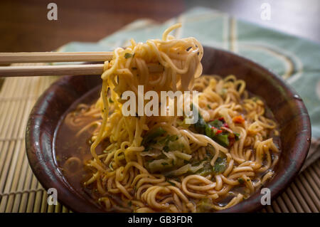 Würzige asiatische Ramen Nudelsuppe mit Stäbchen in Holzschale Stockfoto