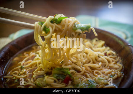 Würzige asiatische Ramen Nudelsuppe mit Stäbchen in Holzschale Stockfoto