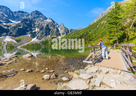 Frau Tourist auf Holzsteg Stand und sah bei Morskie Oko See, Tatra-Gebirge in Polen Stockfoto