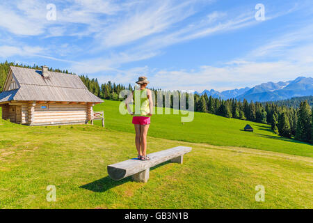 Junge Frau Tourist auf Bank auf grüner Wiese Stand und sah in der hohen Tatra, Polen Stockfoto