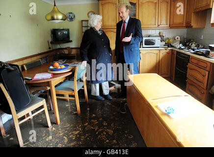 John Healey, Minister für Hochwasserrückgewinnung, spricht mit dem pensionierten Arzt Elspeth Wilkinson in ihrer überfluteten Küche ihres Hauses in Morpeth, Northumberland. Stockfoto