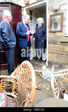 John Healey, Minister für die Wiederherstellung der Überschwemmungen, Mitte, mit Denis Murphy, Parlamentsabgeordneter für Wansbeck, links , Sprecht mit der pensionierten Ärztin Elspeth Wilkinson in ihrem Haus in Morpeth, Northumberland. Stockfoto