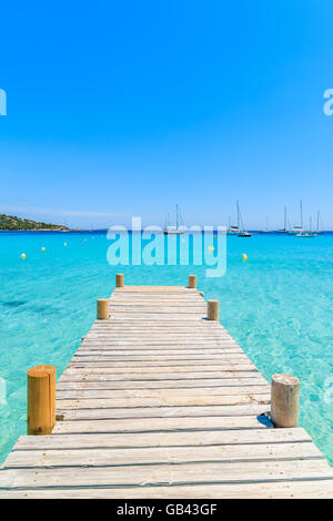 Hölzerne Pier und kristallklares türkisfarbenes Meerwasser am Strand von Santa Giulia, Korsika, Frankreich Stockfoto