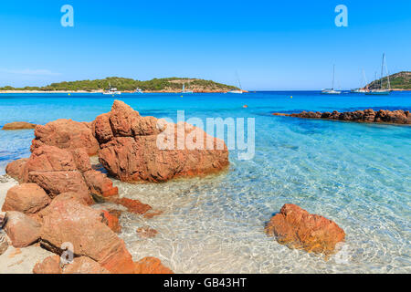 Rote Farbe Felsen am Strand von Santa Giulia mit azurblauen Meerwasser, Korsika, Frankreich Stockfoto