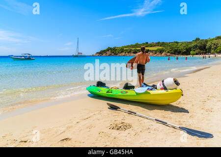 Korsika, Frankreich - 25. Juni 2015: junger Mann stehend mit dem Kajak und Vorbereitung zum Surfen am Sandstrand Grande Sperone, Cors Stockfoto