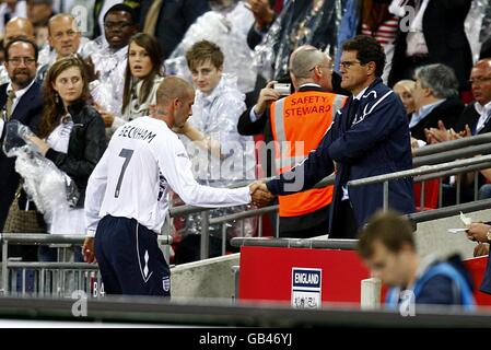 Der Engländer David Beckham (links) schüttelt sich nach seiner Substitution in den Tribünen die Hände mit Manager Fabio Capello. Stockfoto