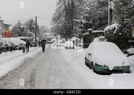 Ein Personen-Spaziergänge entlang einer verschneiten Straße in Tunbridge Wells, Kent, UK mit Schnee bedeckten Autos auf der Straße geparkt Stockfoto