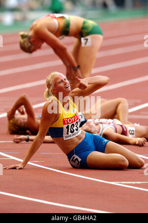 Die Schwedin Carolina Kluft schafft es, den Daumen nach oben zu heben, um die Goldmedaille zu feiern, während ihre Mitkonkurrenten erschöpft um sie herum liegen Stockfoto