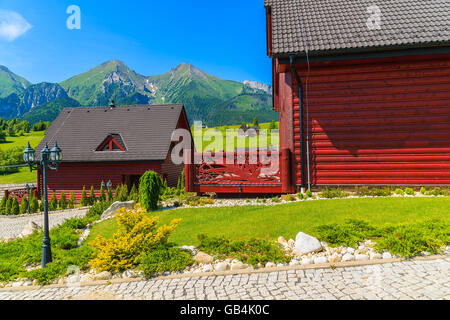 Holzhäuser auf grüner Wiese mit Tatry Bielskie Bergen im Hintergrund im Sommer, Slowakei Stockfoto