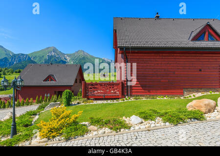 Holzhäuser auf grüner Wiese mit Tatry Bielskie Bergen im Hintergrund im Sommer, Slowakei Stockfoto