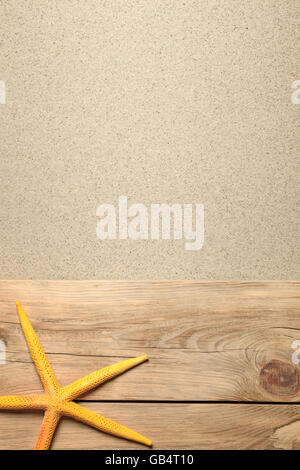 Summer background with yellow starfish on planks and sandy beach Stockfoto