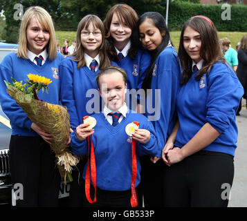 Die Paralympische Schwimmerin Eleanor Simmonds, die jüngste Paralympic-Einzelgewinnerin Großbritanniens, wird von den Klassenkameraden Amber Evans, Sophie Adams, Natasha Lacey, Samia Rossaye und Cara D'Alesio bei ihrer Rückkehr an die Olchfa School in Swansea begrüßt. Stockfoto