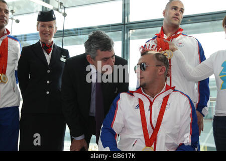 Premierminister Gordon Brown trifft den britischen Paralympischen Schützen Matt Skelhon vom britischen Paralympischen Team, als sie am Londoner Flughafen Heathrow aus Peking aussteigen. Stockfoto