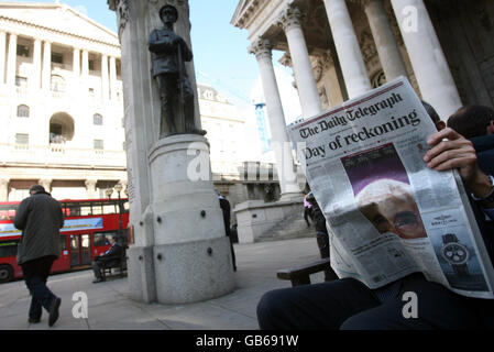 Ein Mann liest eine Zeitung vor der Bank of England in der City of London. Stockfoto