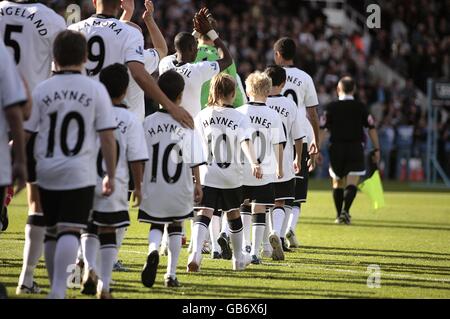 Fulhams Spieler und Maskottchen gehen mit Johnny auf den Platz Haynes-Shirts Stockfoto