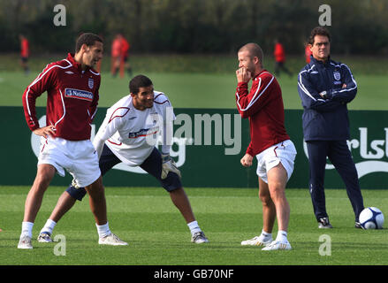 Der englische Rio Ferdinand (links) spricht mit David James (Mitte) und David Beckham (rechts), die Fabio Capello während eines Trainings in London Colney, Hertfordshire, beobachtet hat. Stockfoto