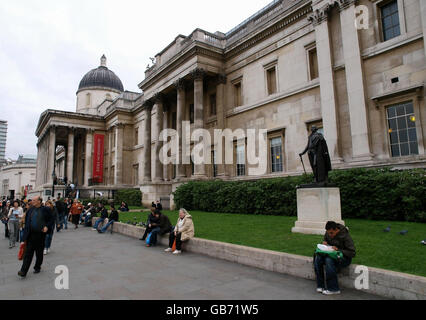 Touristen sitzen in der Nähe einer der Statuen in den Springbrunnen auf dem Londoner Trafalgar Square, mit der National Gallery im Hintergrund. Stockfoto