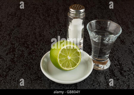 Silberne mexikanische Tequila mit Kalk auf schwarzem Hintergrund. Tequila shot Stockfoto