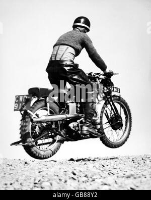 Motorradfahren - Internationale Sechs-Tage-Probefahrt - Vorversuche - Camberley Heath. C Rogers hebt ab, als er auf seinem Royal Enfield den Red Road Hill erreicht. Stockfoto