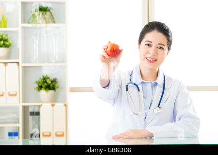 Junge asiatische Ernährungsberaterin hält einen Apfel, gesundes Essen Stockfoto